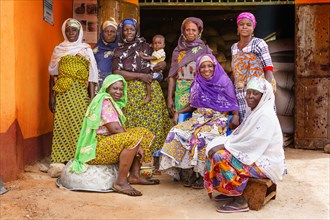 These West African women wearing traditional colorful dress pose for the camera in their village ca. 21 February 2018