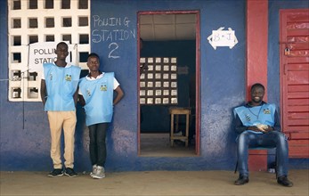 Three poll workers stand outside a polling station in Sierra Leone which marked a peaceful transfer of power from a ruling party to the opposition when Julius Maada Bio of the Sierra Leone People's Pa...