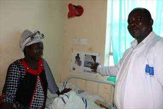 Boaz Nyongesa uses a job aid to explain the importance of breasfeeding and ITN usage to new mother Rose Chege in Kenya ca. 14 April 2015