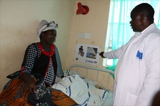 Boaz Nyongesa uses a job aid to explain the importance of breasfeeding and ITN usage to new mother Rose Chege ca. 14 April 2015