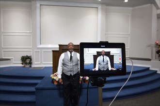 During the Covid-19 pandemic, some churches chose to record sermons to play on their websites and through streaming services to replace in person worship. Here, a technician records a minister as he p...