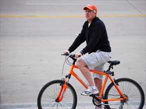 Man on a bicycle pauses his morning ride to watch a group of people protesting at a Tea Party rally ca. 2009