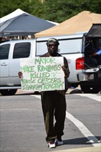 Dallas, Texas, USA. 10th July, 2016 An African American man holds a counter protest sign at a gathering of citizens in front of Dallas police headqurters who have come to show support for the police