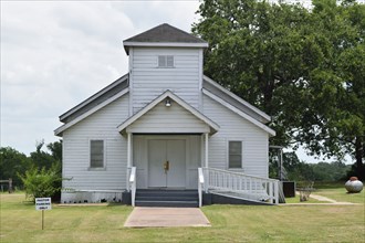 Old white church building NE of Brenham, TX, pastor parking only sign in lower left side of image