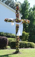 A cross covered with flowers stands in front of a church in Benton, MS