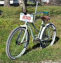A bicycle with a JESUS license plate sitting in the front yard of a home in a small Texas town
