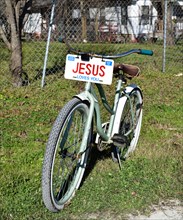 A bicycle with a JESUS license plate sitting in the front yard of a home in a small Texas town