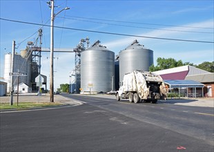Garbage truck drives by Total Grain Marketing and OKAW Farmers Co-op / grain elevators in Arcola, Illinois