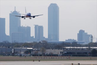 A Southwest Airlines plane landing at Love Field in Dallas, TX; Downtown Dallas in the background (ca. 2010, note the old color scheme)