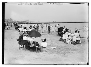 Over-dressed revelers relax on the beach at Coney Island