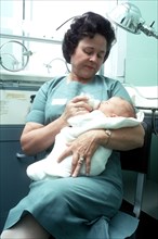 A nurse feeds an infant.