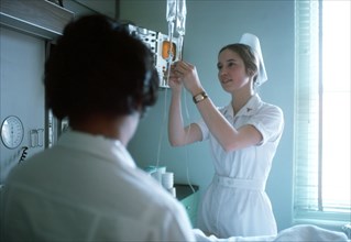 A nurse adjusts the flow of an intravenous solution.