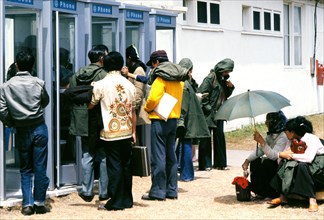 Vietnamese refugees wait to use telephones at a temporary housing facility.