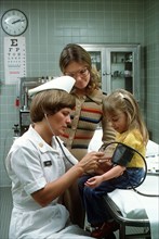 A nurse takes a child's blood pressure.