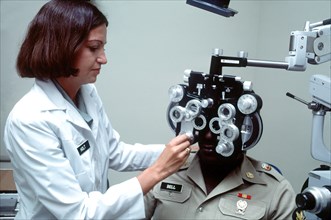 A female U.S. Army optometrist conducts a vision test.