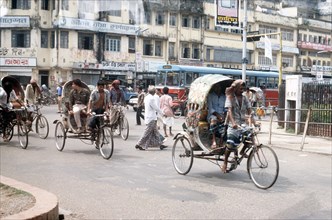 Vehicles and pedestrians move about the streets of Dhaka