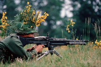 An camouflaged infantryman armed with an M60 machine gun.