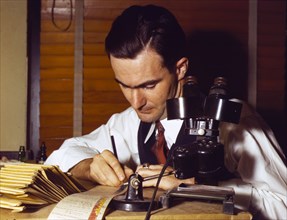 1940s man examining paper work in an office