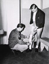 A young man being fitted with a prosthetic leg ca. mid
