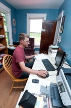 An organic farmer sits at the computer in his office
