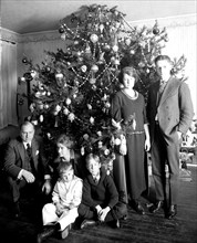 Family in front of their Christmas tree at home in early 1900s ca. 1922