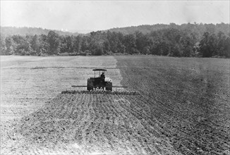 Farmer on a tractor working in a field with disc implement
