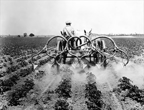 Farmer riding tractor in field spraying fertilizer on his crops