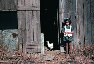 Girl next to barn with chicken