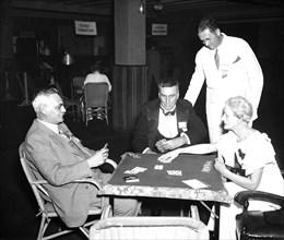 Group of men and and one woman playing cards