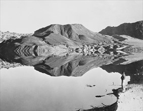 Landscape with man viewing mountain reflection