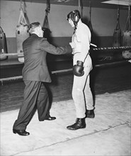 Man in a suit throwing a punch at the torso of a boxer