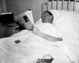 Man in hospital bed smoking a cigarette