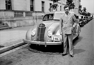 Senator Huey P. Long standing by an automobile