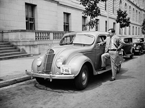 Senator Huey P. Long standing by automobile