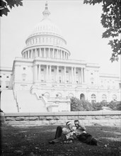 Two people sitting in lawn in front of U.S. Capitol