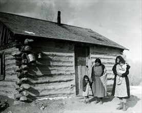 Two Women and Two Children in Front of Cabin