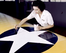 Woman defense industry worker paints the American insignia