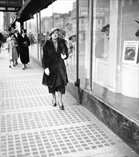 Woman walking down sidewalk in city