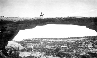 Natural Bridges National Monument in Utah. In this short, we see Dan Perkins (USGS) standing on his horse 'Cap' on top of Owachomo Bridge. ca. 1925