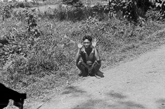 1947 - Medan. Indonesian is squatting with his hands up and makes gesture of surrender - Location: Indonesia, Dutch East Indies