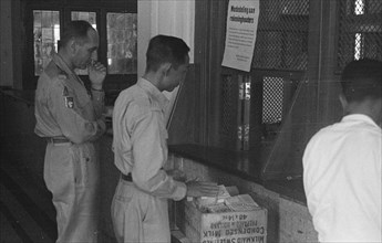 Man receives bundles of banknotes and puts them in a box; Date November 1949; Location Indonesia, Dutch East Indies, Padang, Sumatra