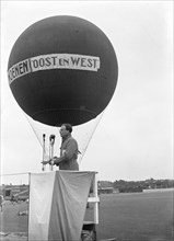 September 28, 1947 - Man speaking in front of hot air balloon at East and West (oost en west)