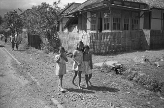 Three girls walk on the street (Gadog?); Date November 15, 1947 Location Indonesia, Dutch East Indies