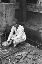 Indonesian woman (baboe?) Busy with a basket at a tap; Date 1947; Location Indonesia, Dutch East Indies
