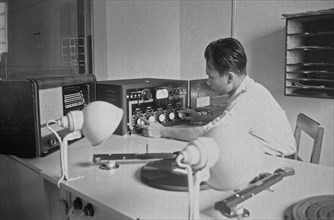 Radio Studio. Technician turns buttons. For him gramophone record players; Date 1947 Location Indonesia, Dutch East Indies