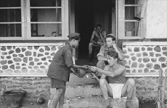 Soldier exchanges a cigarette for a coconut. The young Indonesian wears a kind of uniform. July 21, 1947; Location Bandoeng, Indonesia, Java, Dutch East Indies