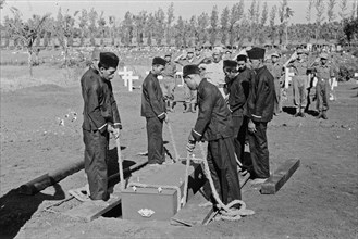 Cemetery workers lowing a coffin into a grave in Indonesia ca. 1947