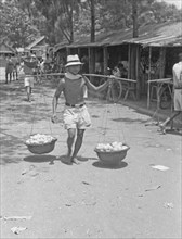 1947 -Fruit seller with baskets on yoke in Indonesia, Dutch East Indies