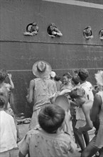November 1946 - Soldiers throw cigarettes from the portholes for the children on the quay - Location: Batavia, Indonesia, Jakarta, Dutch East Indies, Tandjong Priok