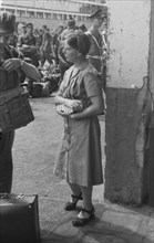 A woman hands out packs of cigarettes at the quay in Batavia, Indonesia, Jakarta, Dutch East Indies ca. 1946